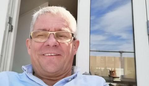 Portræt af Tage Lund der smiler i solen foran sit byhus