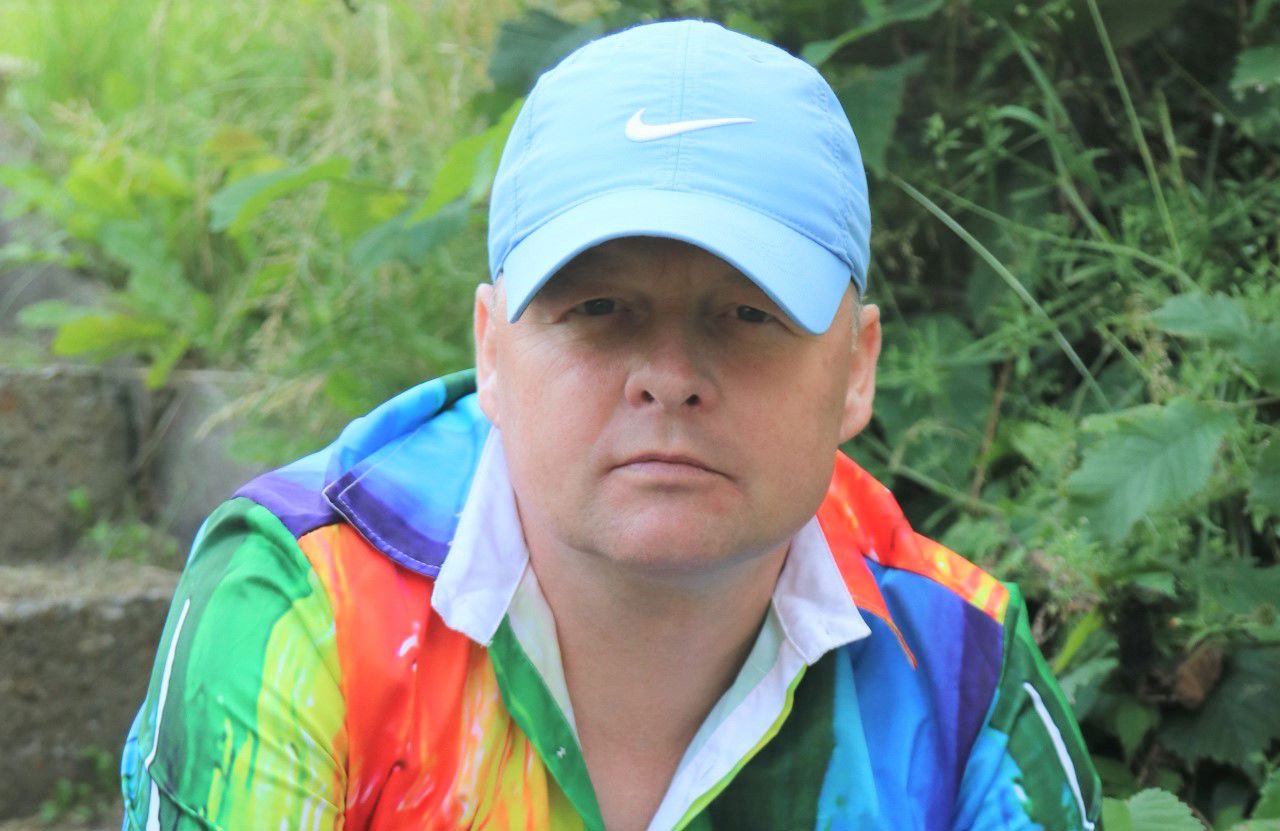 Peter Venø Jensen med lyseblå kasket og regnbuefarvet skjorte ser ind i kameraet