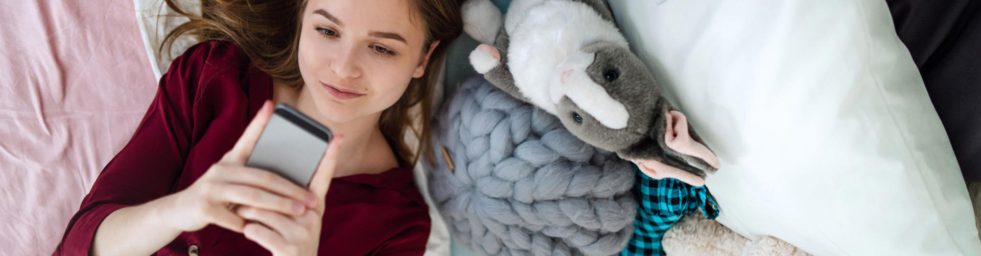 Ung pige som ligger med sin telefon